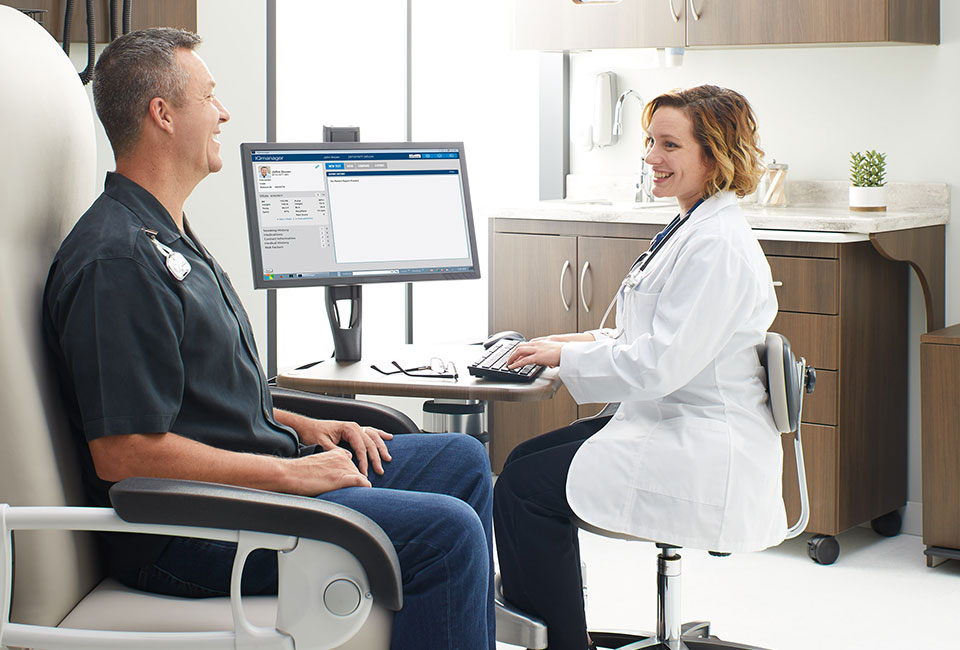 Doctor at mobile workstation with patient in exam chair