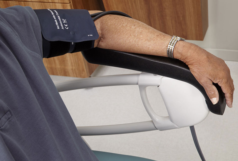 A patient's arm in a Midmark exam chair, connected to a blood pressure cuff.