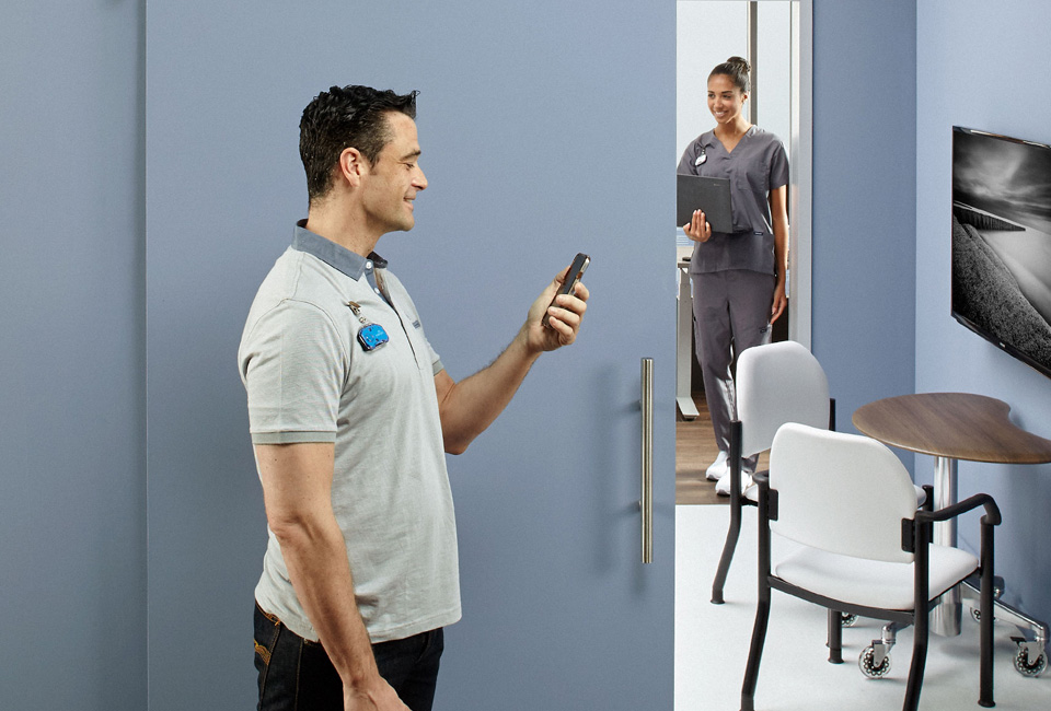 Standing patient looking at phone with nurse in the background