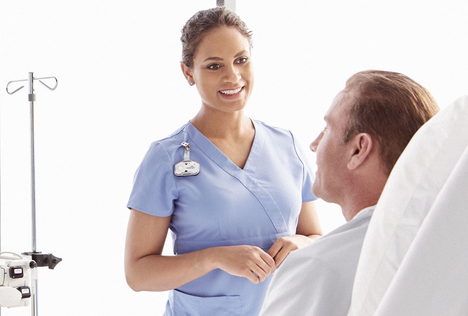 Nurse with Midmark RTLS badge speaking with patient.