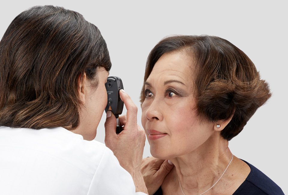 Doctor examining patient's eye with Heine device