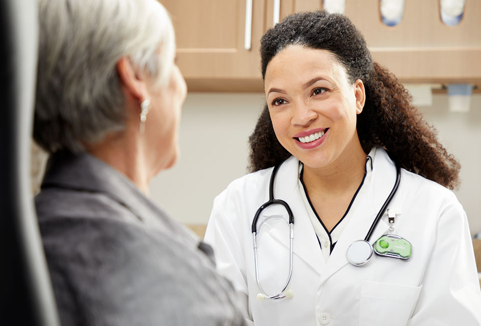 Smiling doctor in conversation with a patient in an exam room