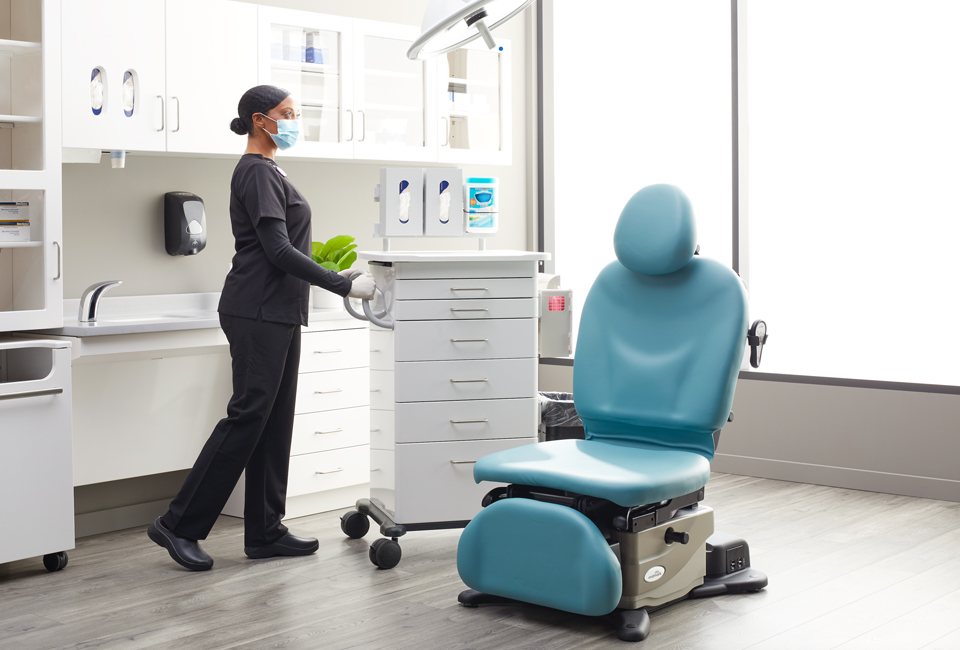 Medical staff moving a procedure cart on casters in an exam room