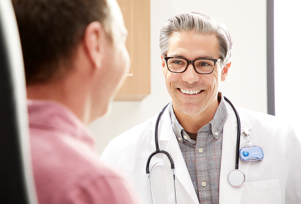 Smiling doctor wearing Midmark badge looking at patient