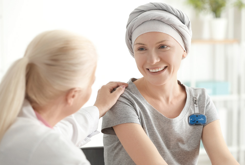 Doctor with hand on oncology patient, wearing Midmark RTLS badge.