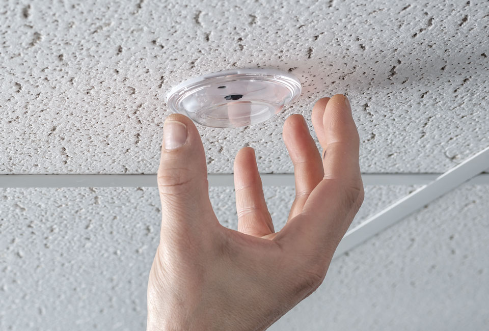 Hand reaching for a sensor on the ceiling