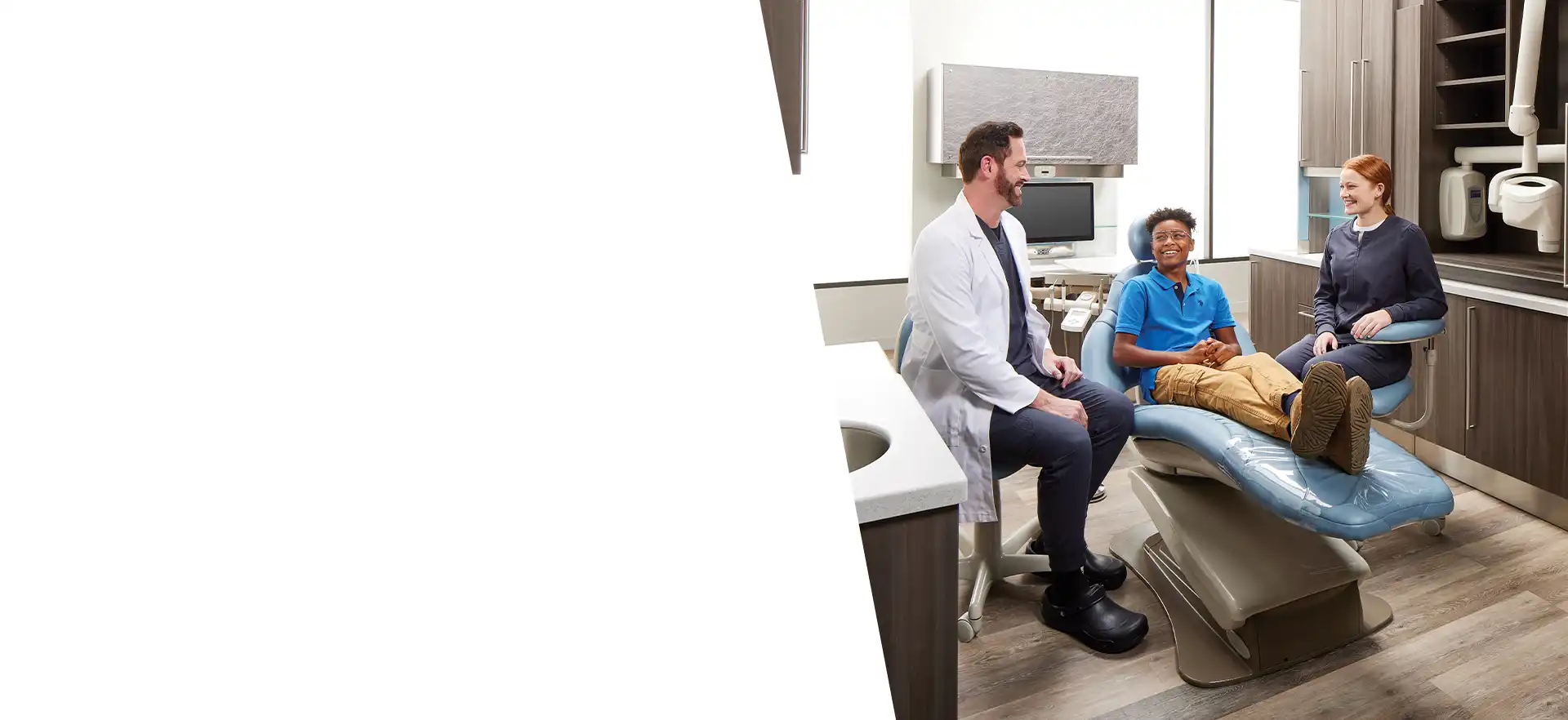 Young male patient speaking with dentist and dental assistant in operatory