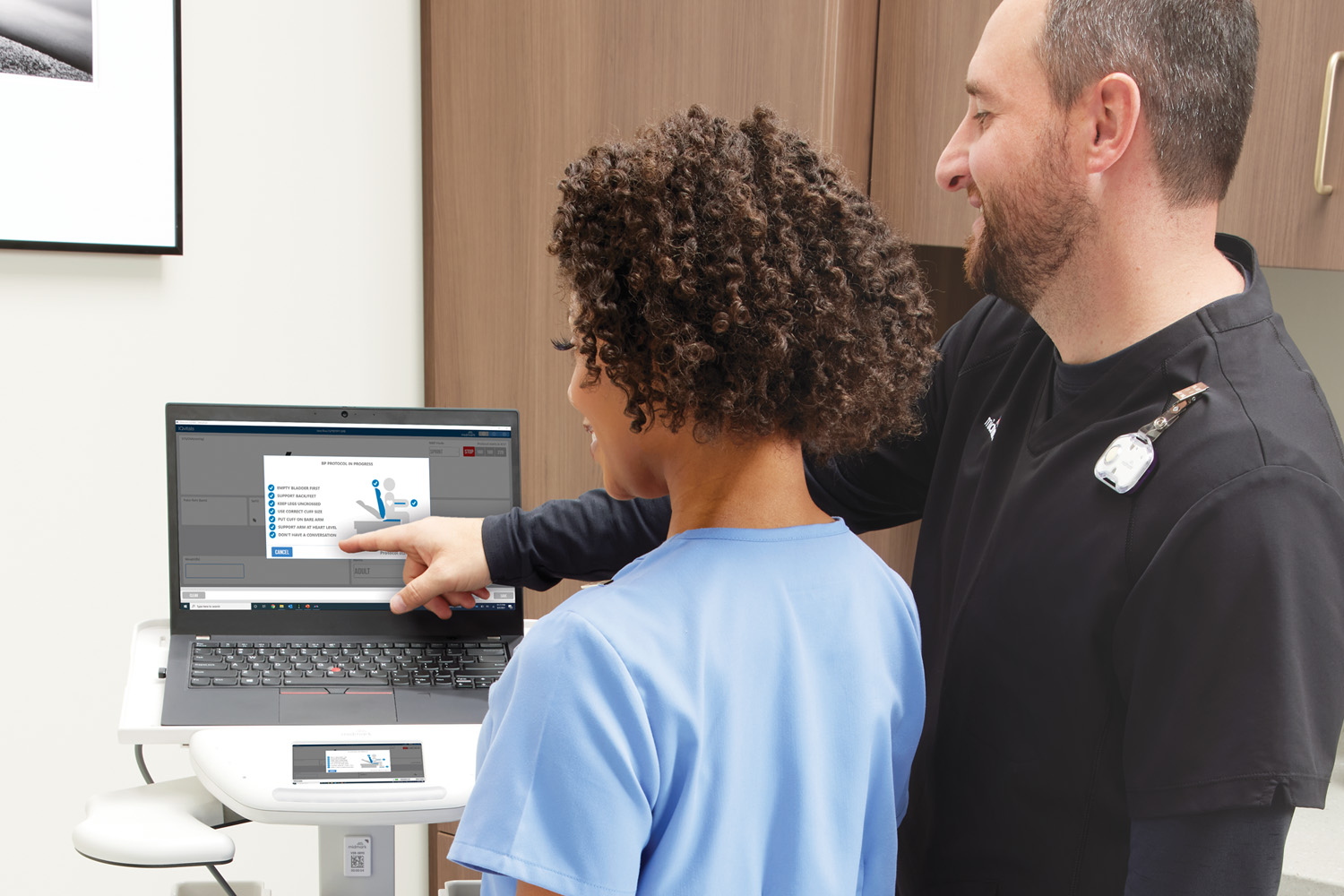 Nurse assisting another nurse with program on a laptop