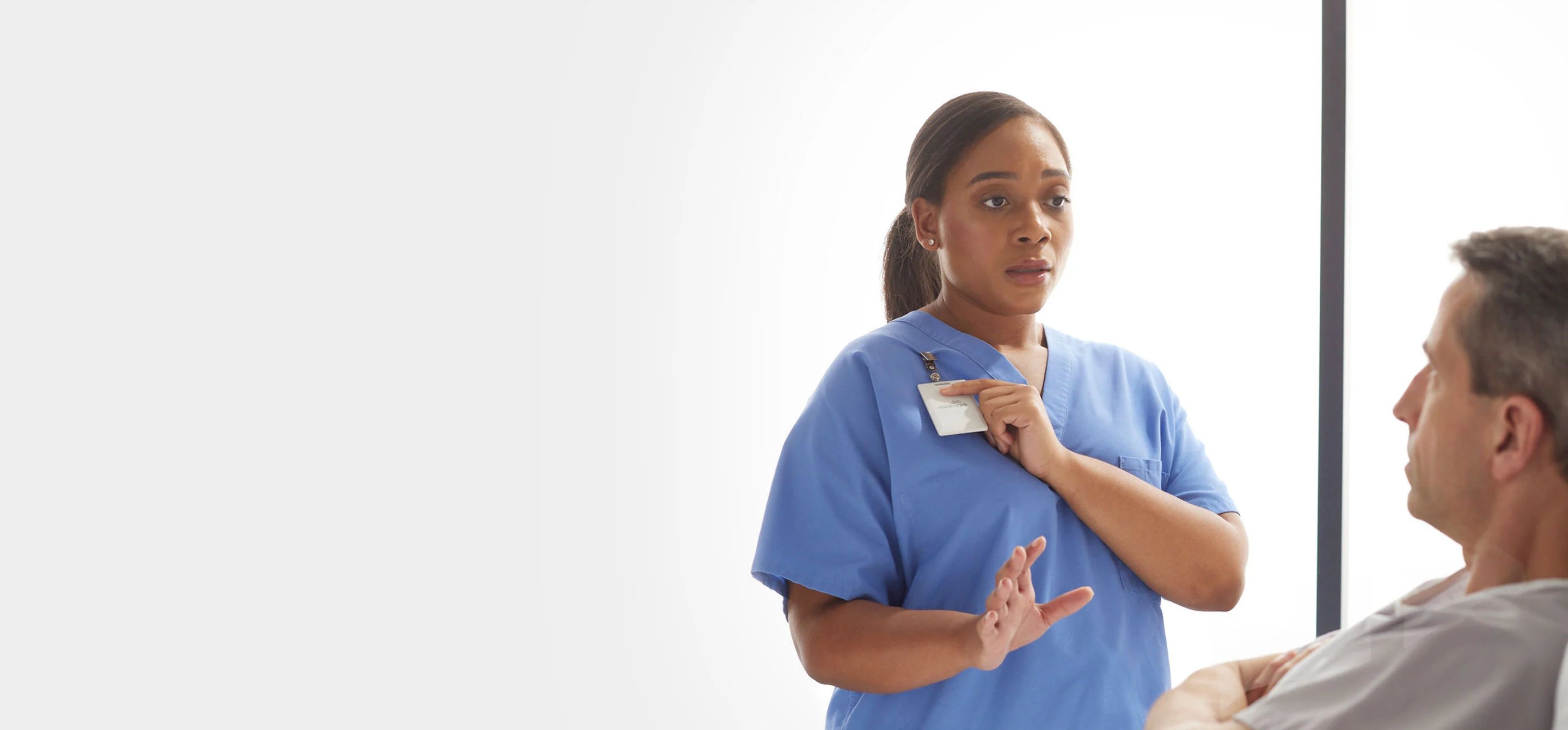 nurse wearing midmark rtls badge and talking to patient